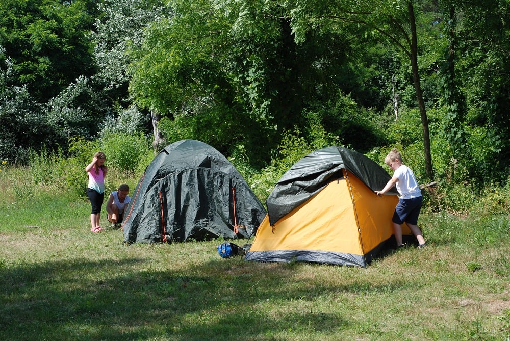 Dzieci rozstawiają namioty. Jasiu po prawej stronie zdjęcia samodzielnie naciąga tropik.
